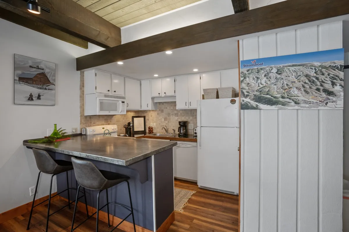 Another perspective on the kitchen displays the island with bar stools, visible high-end appliances, and decorative touches that evoke a sense of warmth and togetherness. The arrangement encourages both cooking and casual conversation.